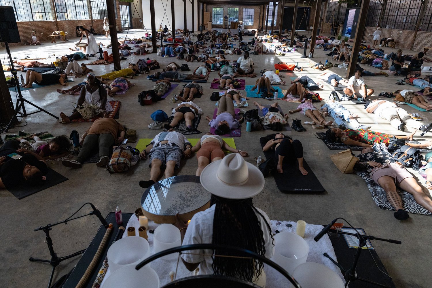 A large-scale Bloom sound bath with hundreds of participants lying in a warehouse venue